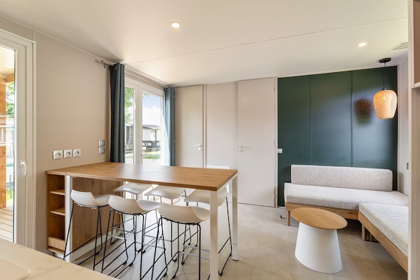 A modern kitchen with a dining area, a sofa, and a hanging light fixture.