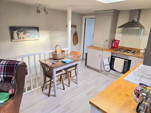 A compact kitchen with a dining area, wooden furniture, and a hanging light fixture. - Cosy tucked-away Barn conversion in Matlock Green (Matlock)