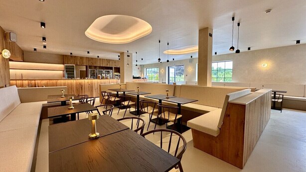 Een modern interieur met een lange gemeenschappelijke tafel, zithoeken en een keuken op de achtergrond.
