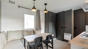 Een moderne keuken met een eethoek, met een lichtkleurige tafel en stoelen, donkere kastjes en hanglampen.