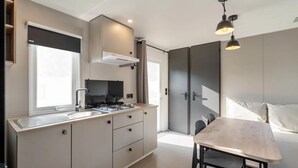 Een moderne keuken met een ingebouwde kookplaat, een groot raam en een eethoek met tafel en stoelen.