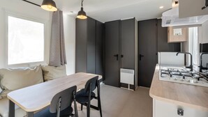 Een moderne keuken met een houten tafel en stoelen, een inbouwfornuis en een raam met uitzicht.