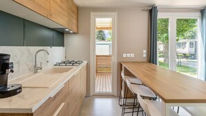 Cocina moderna con estufa a gas, cafetera y mesa de madera con taburetes de bar.