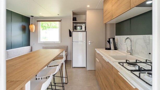 A compact kitchen with a dining area, a microwave, a refrigerator, a coffee maker, and a gas stove. - Camping Papillon Bouillon - Family Vacation Home 6 (Bouillon)