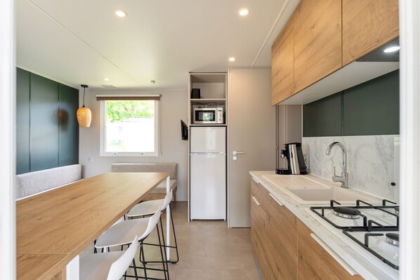 A compact kitchen with a dining area, a microwave, a refrigerator, a coffee maker, and a gas stove.