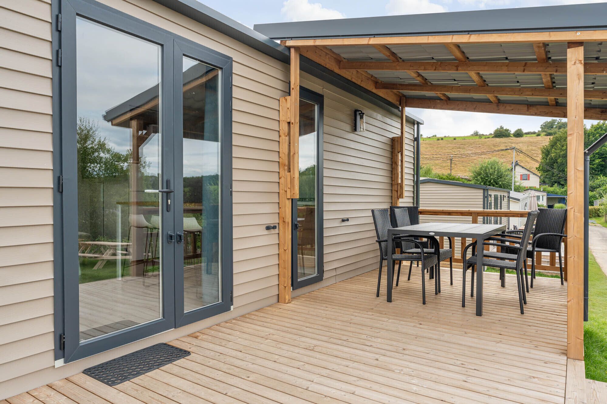 Une terrasse avec une table et des chaises, une porte-fenêtre coulissante et une structure en forme de pergola.