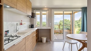 Een moderne keuken met houten kastjes, een spoelbak en een fornuis. Er is een eethoek met een tafel en stoelen.