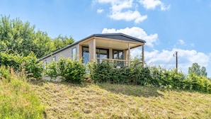 Een modern huis met een overdekte veranda, omringd door weelderige begroeiing en een heldere lucht.