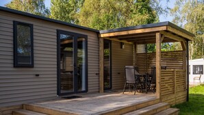 A modern wooden cabin with a deck, sliding glass doors, and a covered patio area. - Camping Papillon Kinrooi - 88 (Kinrooi)