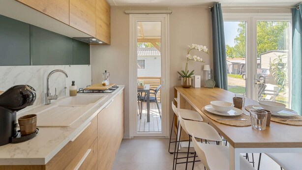 A modern kitchen with a wooden countertop, a coffee machine, and a view of the outdoor patio. - Camping Papillon Kinrooi - La Casetta (Kinrooi)