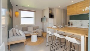 A modern kitchen with a wooden countertop, white bar stools, and a built-in oven. - Camping Papillon Kinrooi - La Casetta (Kinrooi)