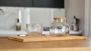 A clear glass pitcher and a glass bowl on a wooden board in a kitchen setting. - Camping Papillon Kinrooi - La Casetta (Kinrooi)