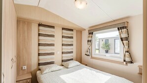 Une chambre à coucher avec un lit, une armoire, une fenêtre avec des rideaux et un luminaire au plafond.