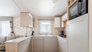 Une petite cuisine équipée d’un four à micro-ondes, d’une cuisinière et d’un évier.