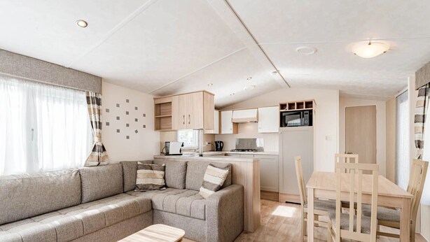 Un intérieur de camping-car moderne comprenant un espace de vie, un coin cuisine et un espace repas.