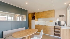 A modern kitchen with wooden cabinets, a built-in microwave, and a gas stove. There is a wooden dining table with white chairs.