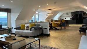 En modern lägenhet i loftstil med matplats, kök och sittgrupp.