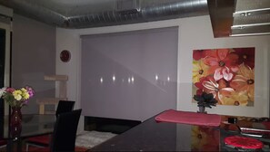 Ein Zimmer mit einem Bett, einem Schreibtisch, einem Stuhl, einer Vase mit Blumen und einem Bild an der Wand.