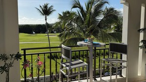 Ein Balkon mit Blick auf einen Golfplatz, ein Tisch mit Stühlen und ein Blumentopf.