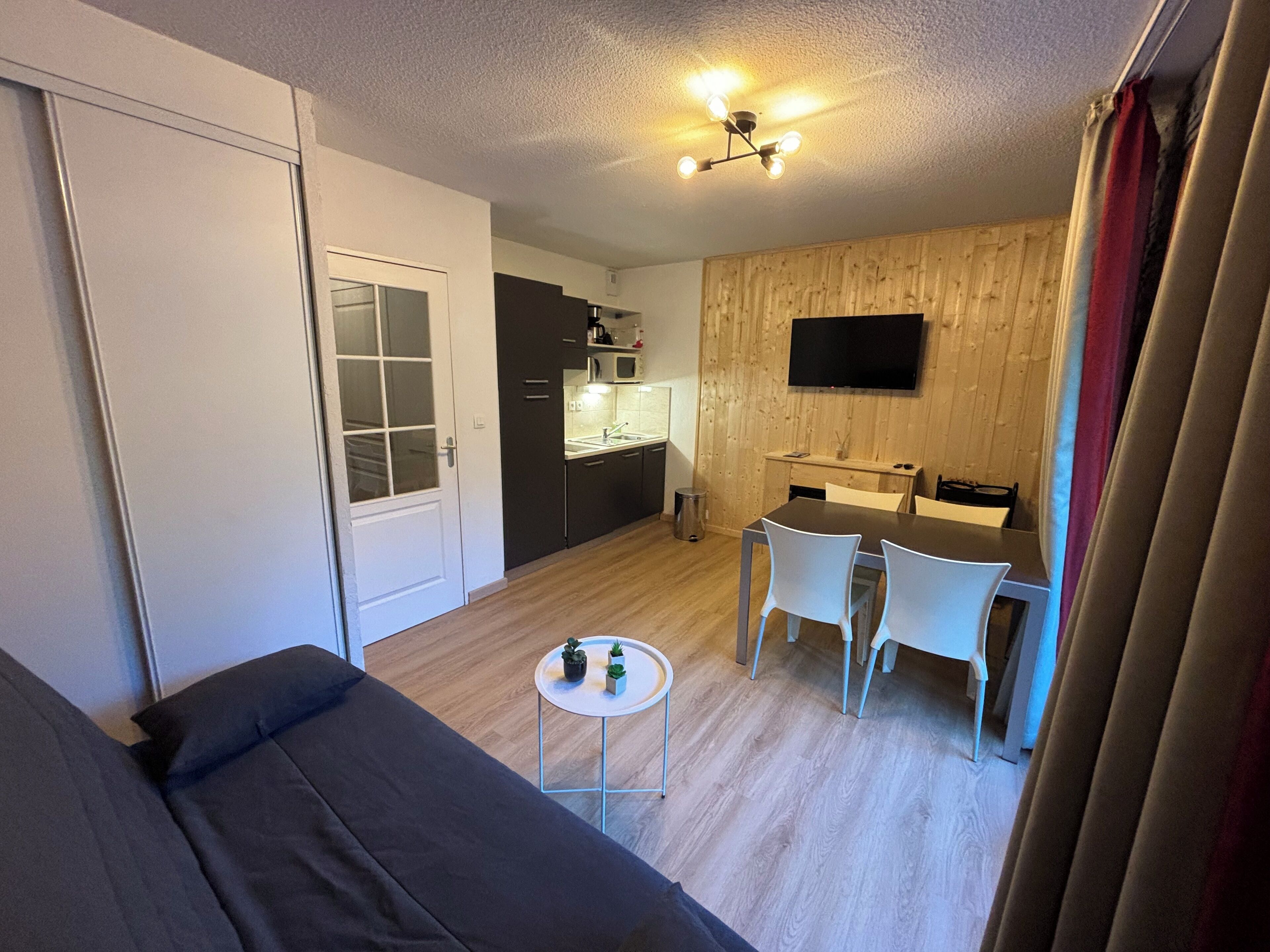 Un espace de vie compact comprenant une kitchenette, un coin repas et un canapé.
