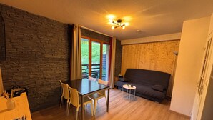 Een gezellige kamer met een stenen muur, een houten vloer, een eettafel met stoelen, een bank en een klein bijzettafeltje.