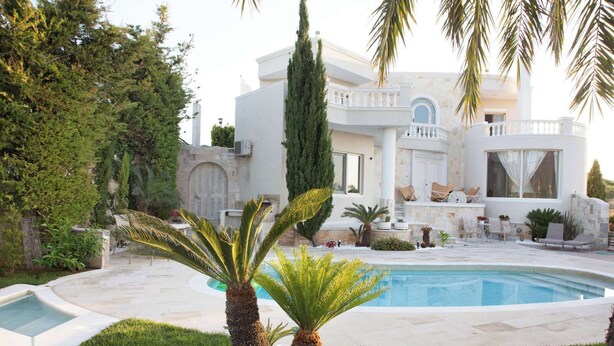 Uma villa luxuosa com piscina, um jardim bem cuidado e uma entrada imponente.
