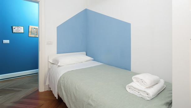 Una camera da letto con un letto, una parete azzurra e due quadri appesi.
