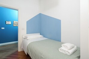 Una camera da letto con un letto, una parete azzurra e due quadri appesi.