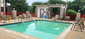 Une piscine équipée d’un poste de surveillance pour sauveteur, d’une bouée de sauvetage et d’un panneau d’avertissement.