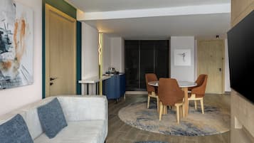 A modern living room with a sofa, a dining table with chairs, and a TV.