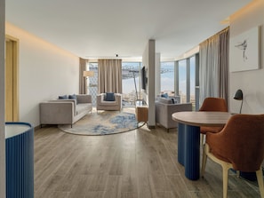 A modern hotel room with a living area, a dining table, and a view of the cityscape. - voco Cairo Arabella Plaza by IHG (New Cairo)