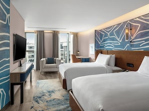 Une chambre d’hôtel avec deux lits, une télévision, un bureau, une chaise et une vue sur la ville.