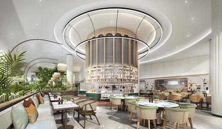 A modern restaurant with a central column, multiple seating areas, and a variety of table settings.