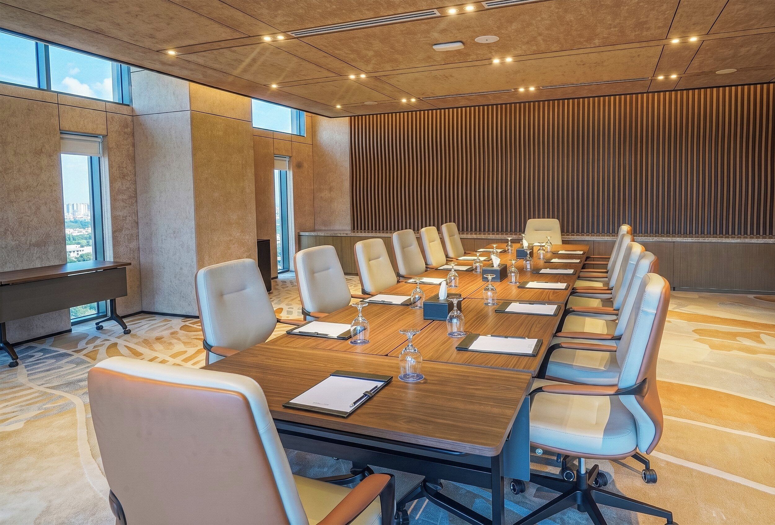 A conference room with a long table, multiple chairs, and a view of the city through large windows.