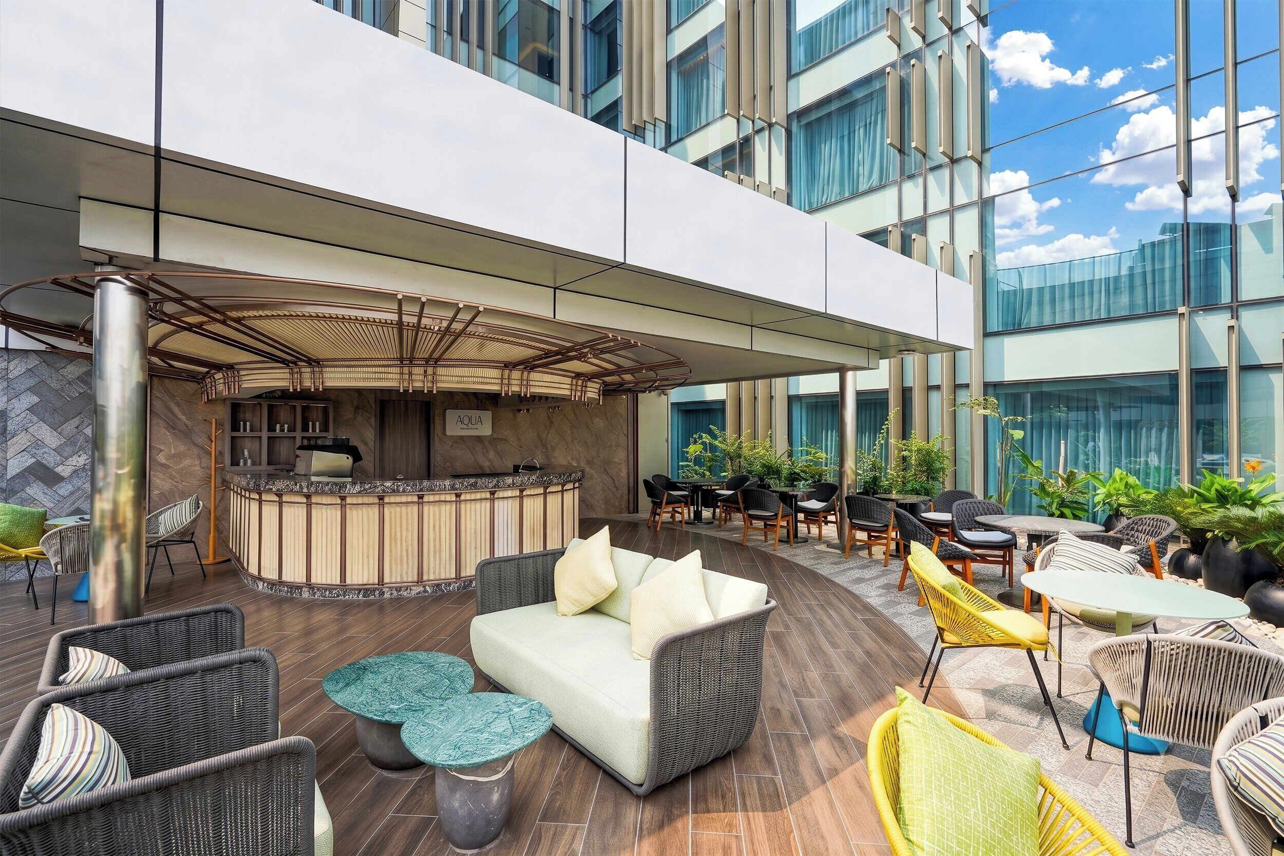 Un vaste espace de détente extérieur, aménagé avec des sièges, un bar et un comptoir d’accueil.
