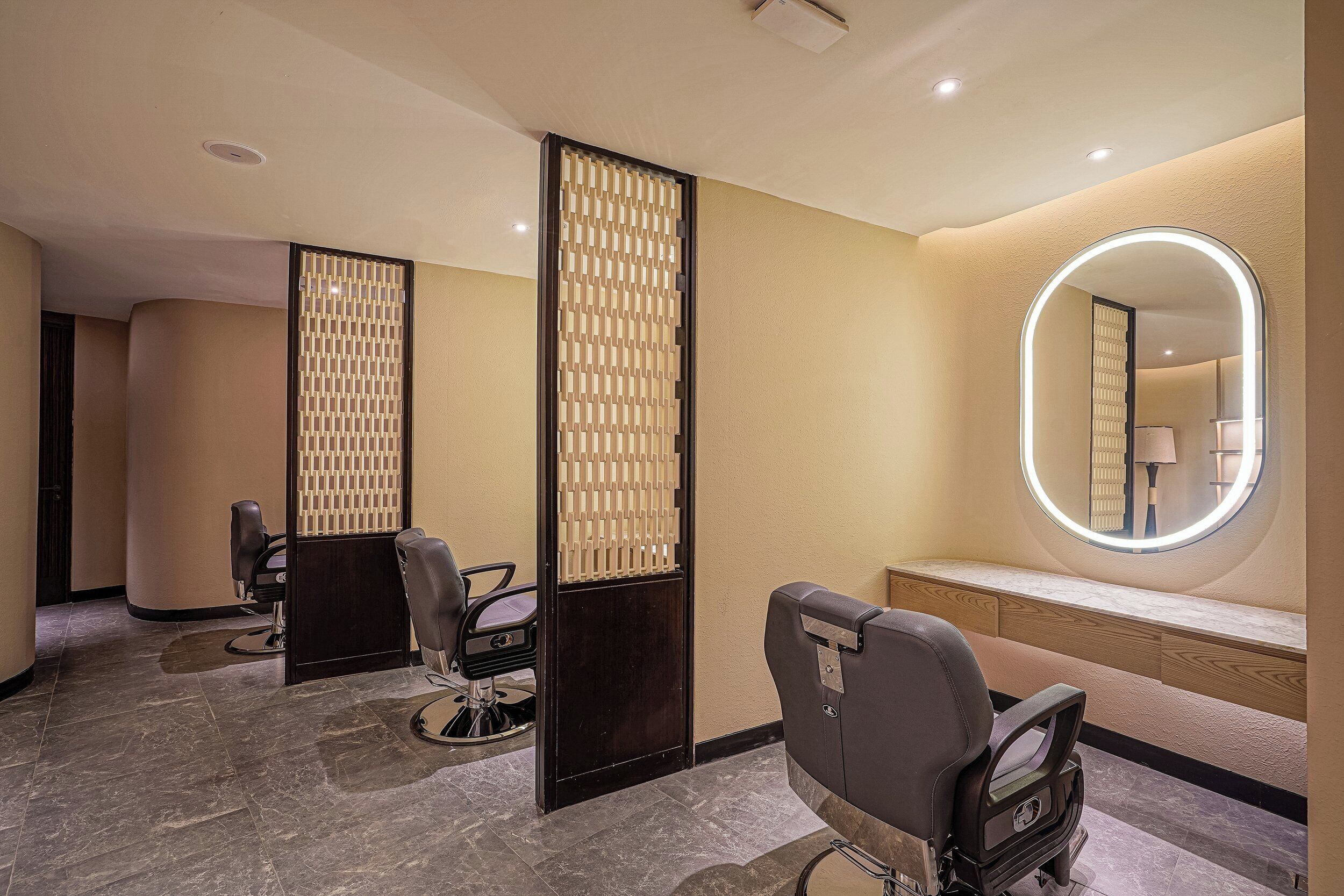 A hair salon with three chairs, a mirror, and a decorative partition.