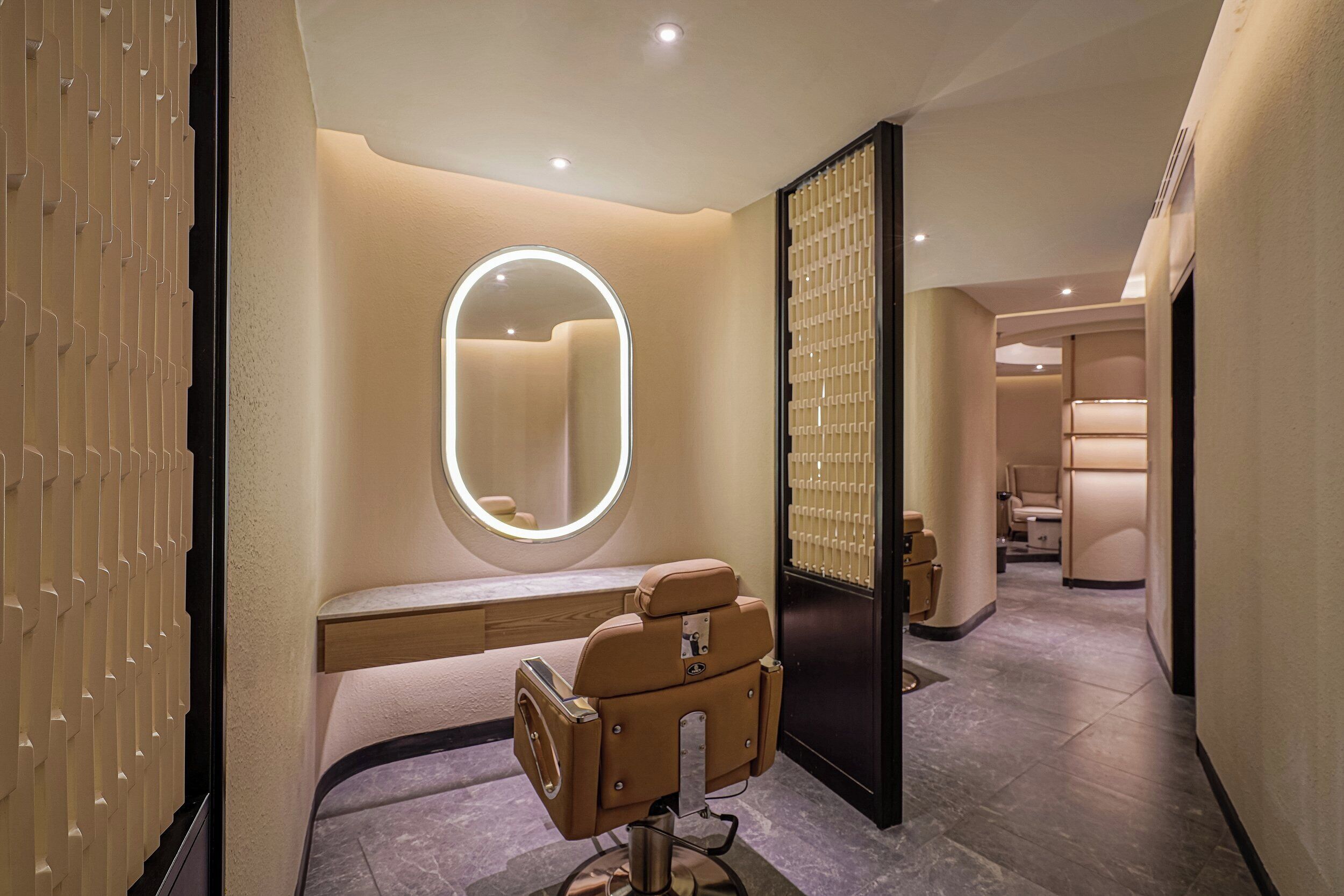 A modern bathroom with a vanity, a mirror, and a seating area.