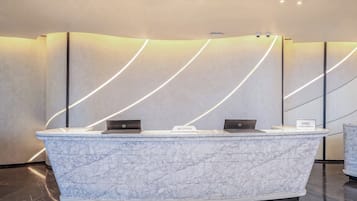 A reception desk with a marble top, two laptops, and a sign indicating 'IHG Hotels & Resorts.'