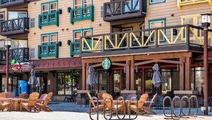Een gebouw met een Starbucks, terras met stoelen en een bord voor Mountain Clothing & Accessories.