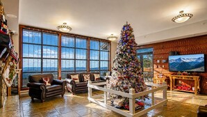 Een ruime woonkamer met een grote kerstboom, leren banken, een houten salontafel en een televisie.