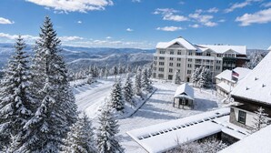 Een bergresort bedekt met sneeuw, met een groot gebouw, vermoedelijk een hotel, met meerdere verdiepingen en een opvallende Amerikaanse vlag.