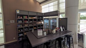 Un área de bar moderna con mostrador, taburetes y estantes llenos de aperitivos y bebidas.
