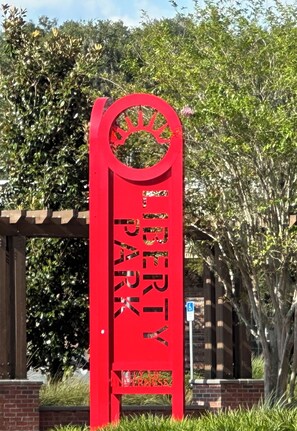 Un letrero rojo con la inscripción 'LIBERTY PARK' y un letrero de estacionamiento azul con el número '8'.