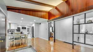 A spacious kitchen with wooden flooring, a dining area with a marble floor, and a modern design with wooden paneling on the walls. - Marvelous 3-bedroom townhome with  Heated floor Manchester (Manchester)