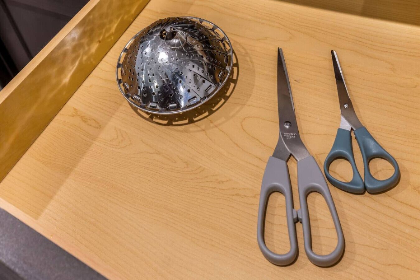 A wooden tray with a metal colander and a pair of scissors.