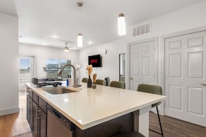 A modern kitchen with a central island, stainless steel appliances, and pendant lighting. - Grand Prairie 1BR | IKEA, Epic Waters, Bass Pro (Grand Prairie)