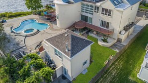 A modern two-story house with a swimming pool, a covered patio, and a view of a lake. - Elegant Waterfront Stay + Bay + Sunset Views (Sea Bright)