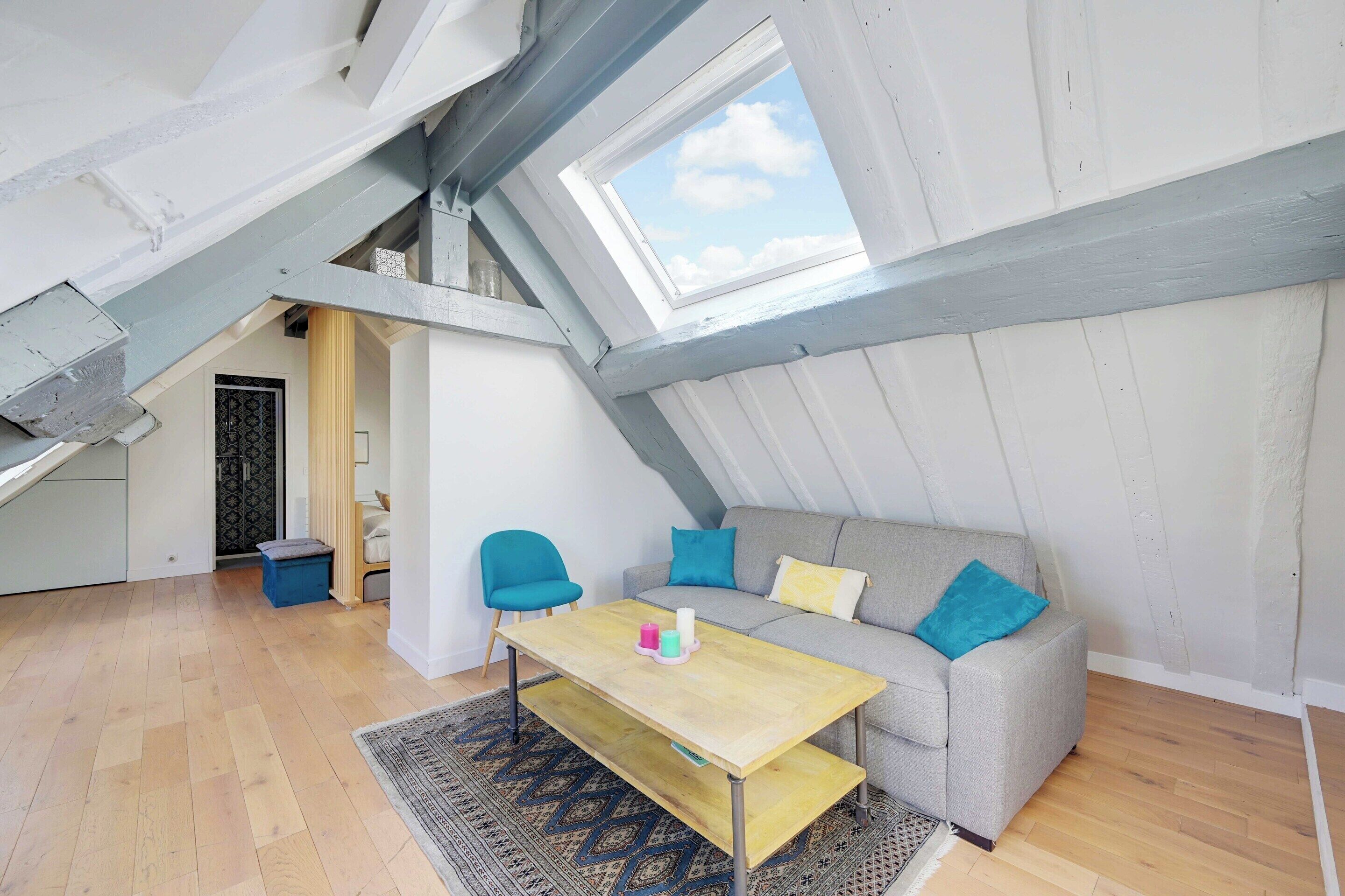Una camera in stile loft con soffitto spiovente, un divano, un tavolo e vista tramite un lucernario.