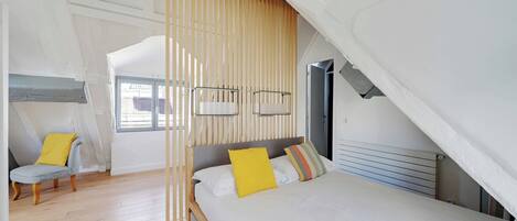 A bedroom with a bed, a chair, and a window.