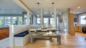 A modern kitchen with a built-in bench, large windows, and a view of the outdoors. - 3-home Coastal Retreat w/ Sauna, Firepit & Greenhouse Seabright Haven by Avantstay (Coupeville)